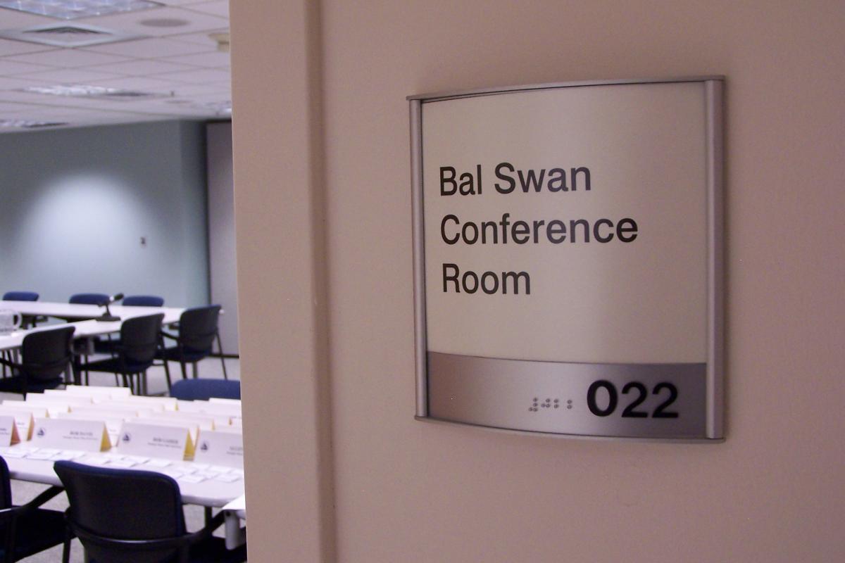 A small rectangular wall sign reads "Bal Swan Conference Room" with the number "022" displayed beneath it. The sign is mounted on a light-colored wall, indicating the room's location and purpose within a building.  Raised lettering and braille are present on the metal plate at the bottom of the sign.