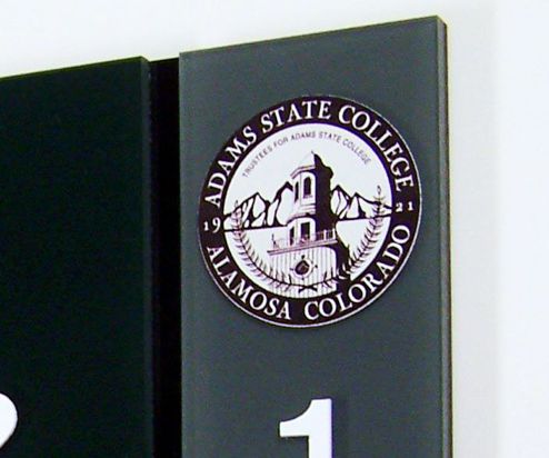 A seal featuring "Adams State College" and "Alamosa Colorado" encircling an illustration of a building with mountains in the background. The segments "1921" and "Trustees for Adams State College" are also visible within the seal. The marker next to the seal displays the number "1".