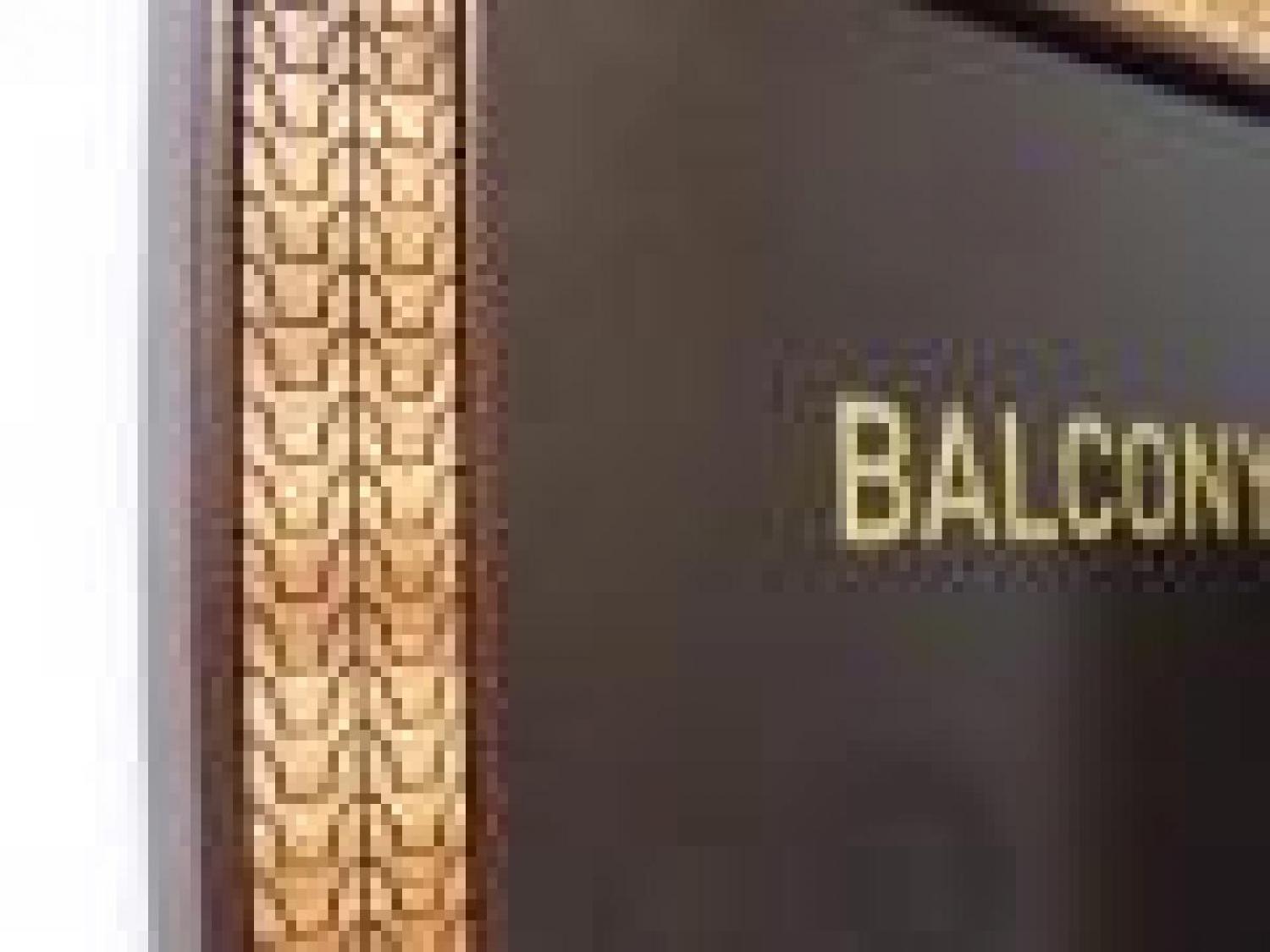 A bathroom sign reading "BALCONY" in gold on a black background. This is a closeup of the decorative, patterned frame.