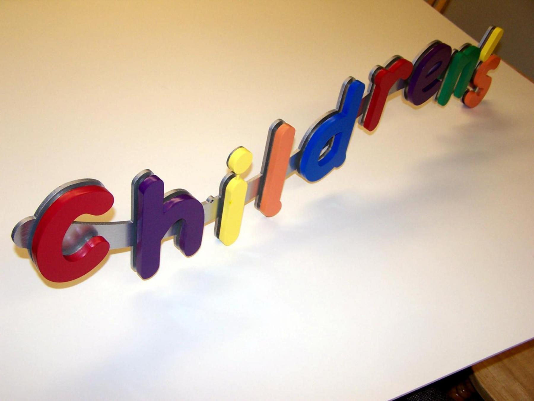 Colorful wooden letters spelling "children's" are arranged in a playful, slightly uneven line on a white background. Each letter is uniquely colored, adding a vibrant, cheerful feel to the composition.