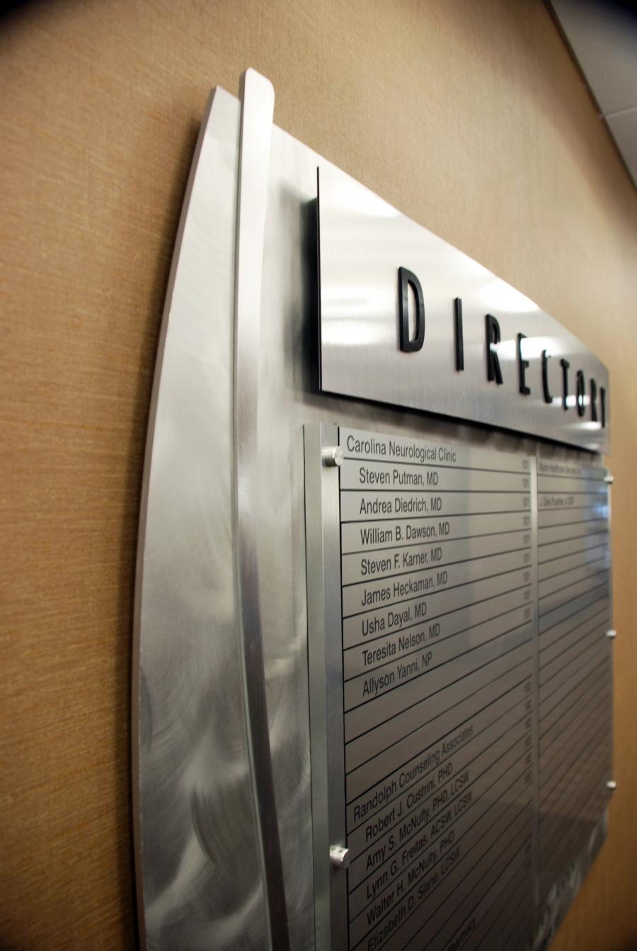 A directory board on the left lists the locations of various departments or offices.  This is a closeup of the Directory from the left side.