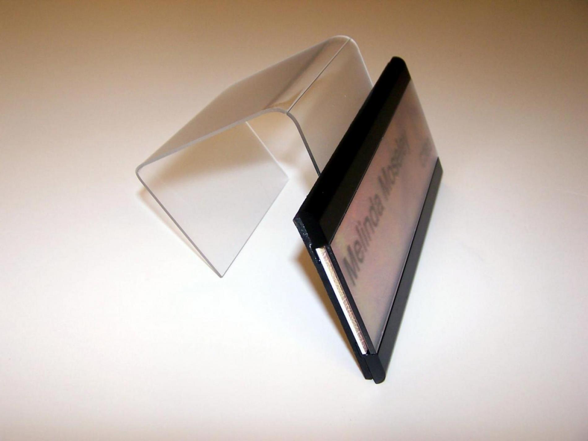 A nameplate with the text "Melinda Moseley" is displayed on a clear stand. The nameplate has a multicolored background with a mix of pink, yellow, and purple hues, and is bordered by black strips at the top and bottom. The label "C303" is visible beneath the stand.