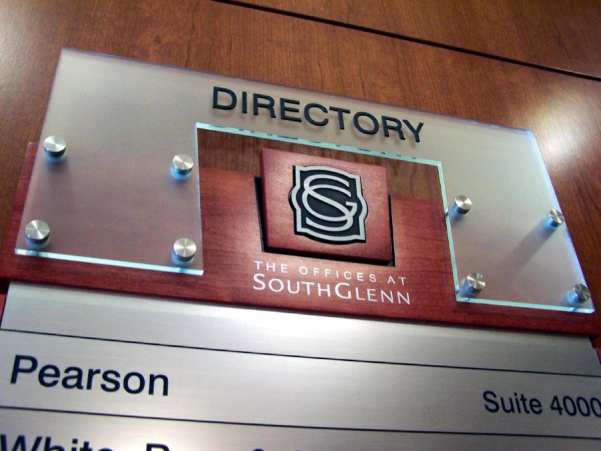 A metallic office directory sign with a clear panel on top reading "DIRECTORY". Below it is a wooden panel featuring the logo and name "The Offices at SouthGlenn". The directory lists names and suite numbers, with "Pearson" and "Suite 4000" clearly visible.
