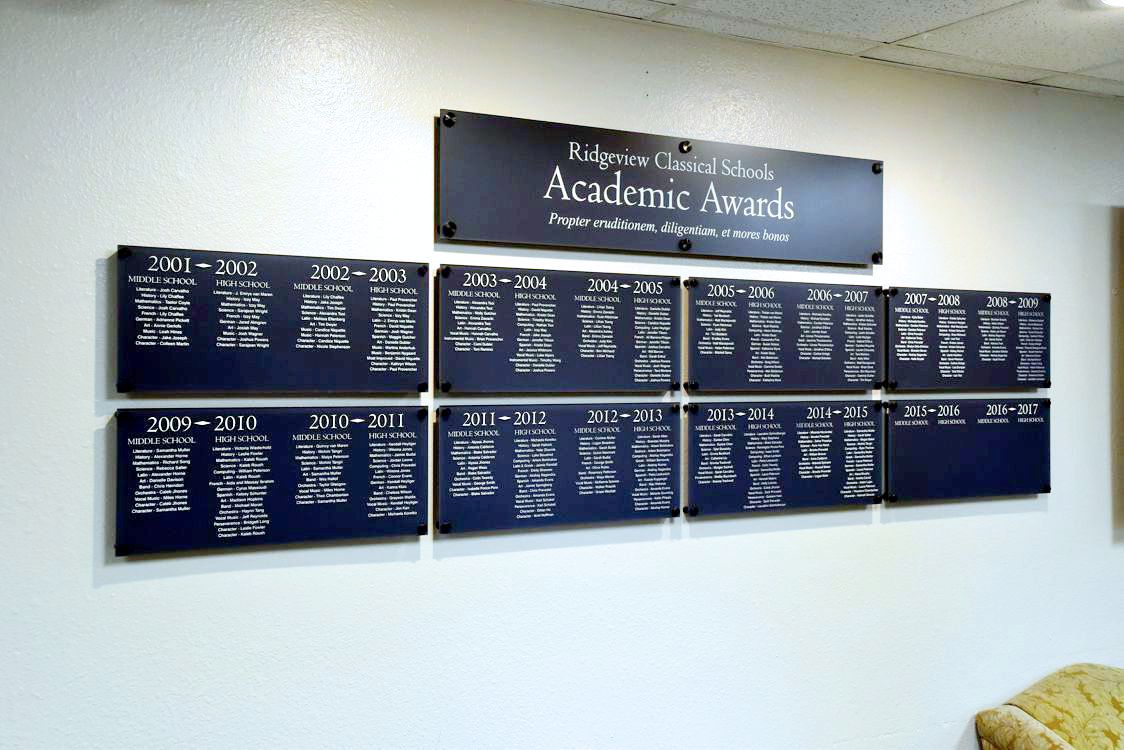 A wall display at Ridgeview Classical Schools showcases Academic Awards from 2001 to 2017. The display consists of multiple black plaques listing student names and their respective achievements for each school year.