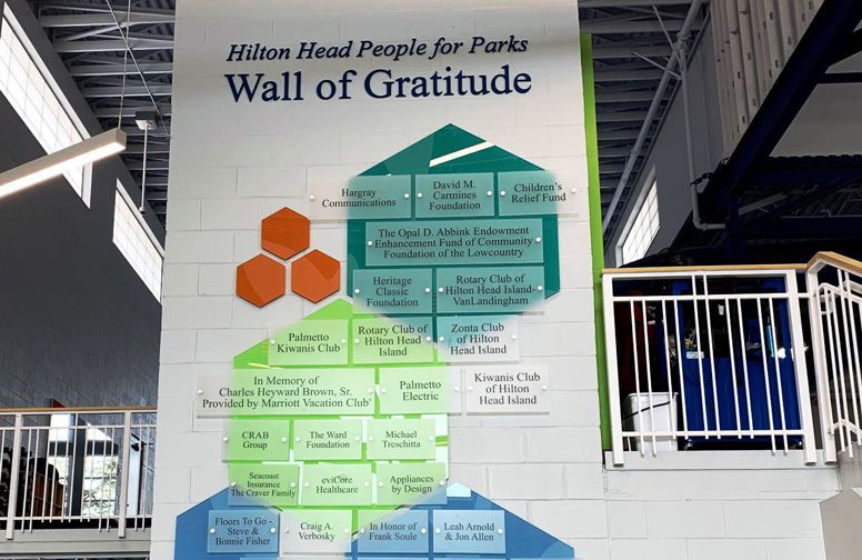 A large wall inside a building features the "Wall of Gratitude" showcasing various donors and organizations that contributed to Hilton Head People for Parks. Names and organizations are listed on colorful blocks arranged in a vertical, pyramid-like structure.