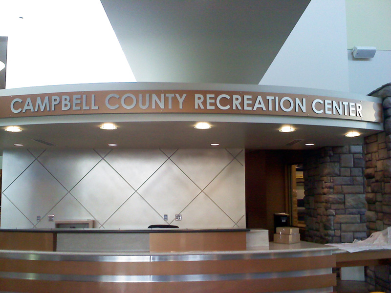 A reception desk at the Campbell County Recreation Center with a curved countertop and a sign above reading "Campbell County Recreation Center."