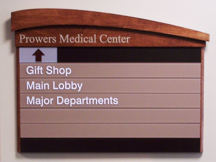 A directory sign at Prowers Medical Center shows directions to the Gift Shop, Main Lobby, and Major Departments, with an arrow pointing upwards. The sign has a wooden header and beige background.