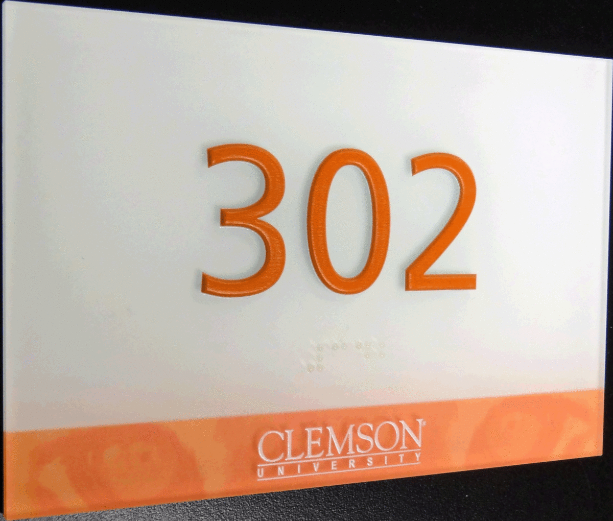 A sign reads "302" in large orange numbers on a white background. Below the numbers, there is a marbled orange strip with "Clemson University" written in white uppercase letters.