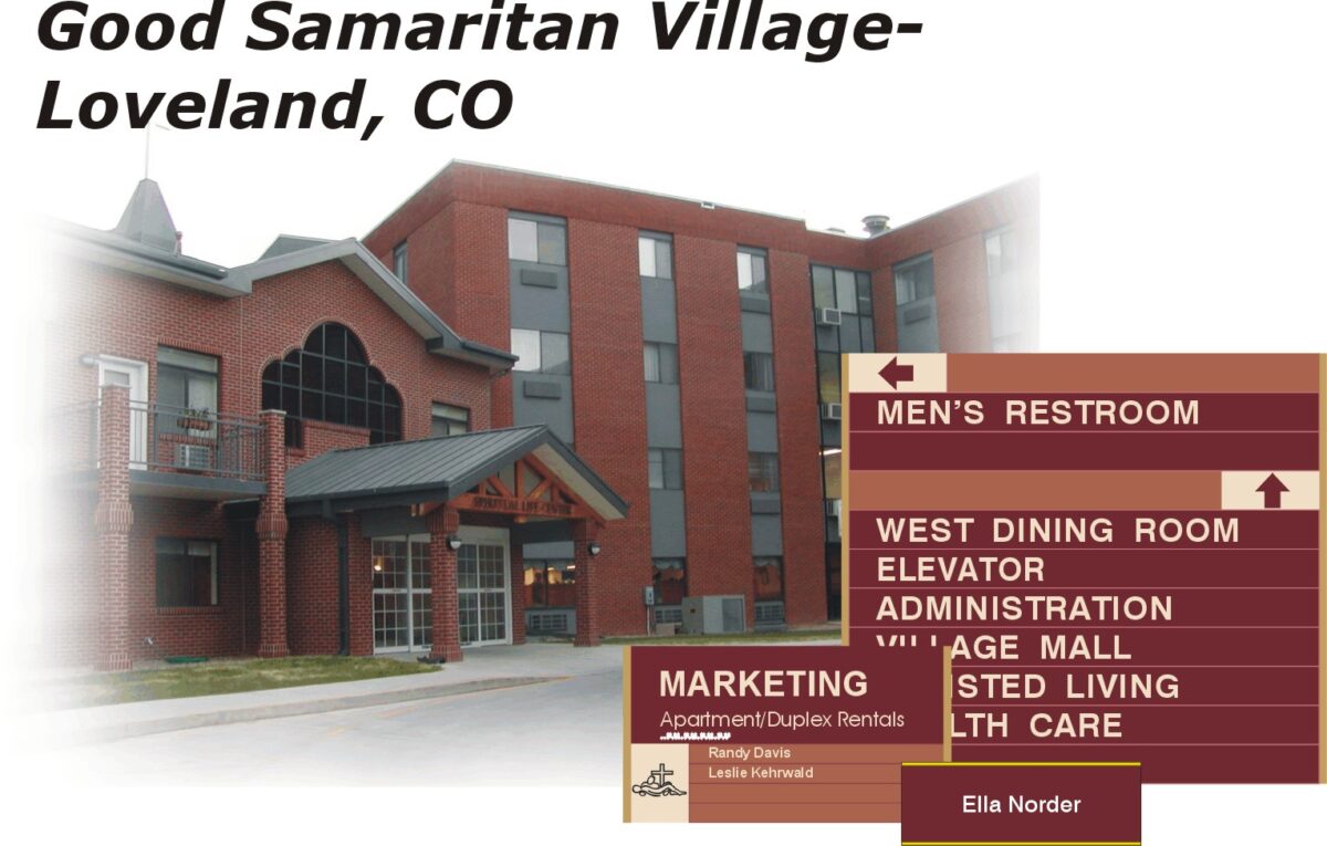 Image depicting a multi-story brick building with a sign in the corner reading "Good Samaritan Village-Loveland, CO." Directional signs include labels for "Men’s Restroom" on top, followed by labels for dining, elevators, administration, and other facilities.