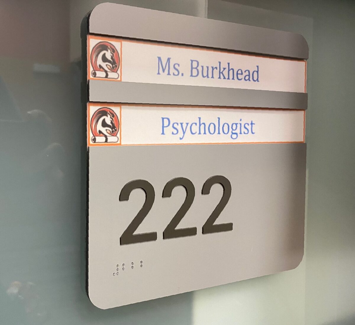 Office sign showing "Ms. Burkhead," "Psychologist," and room number "222" with Braille dots beneath the numerals.