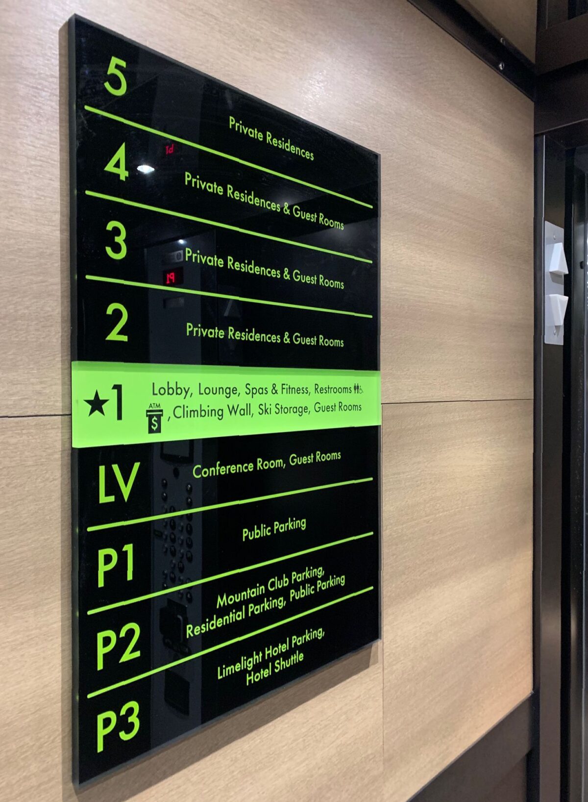 A black and green directory sign in a building. The levels listed are: 5 - private residences; 4 - private residences and guest rooms; 3 - private residences and guest rooms; 2 - private residences and guest rooms; 1 - lobby, lounge, spa & fitness, restaurant, climbing wall, ski storage, guest suites; LV - conference rooms, great rooms; P1, P2, P3 - public parking.