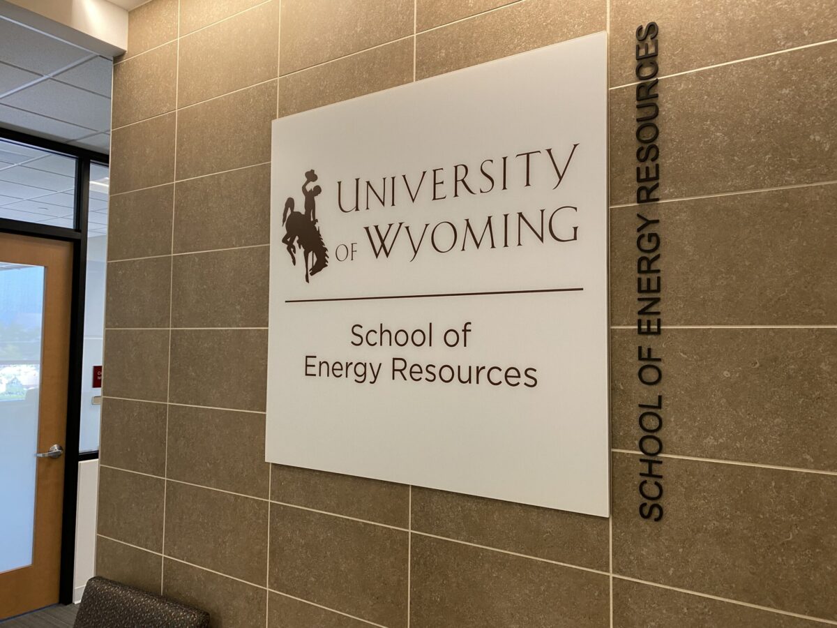 A sign on a tiled wall reads "University of Wyoming School of Energy Resources" with the school's logo. To the right of the sign, "School of Energy Resources" is written vertically. The area features a door and part of a window.