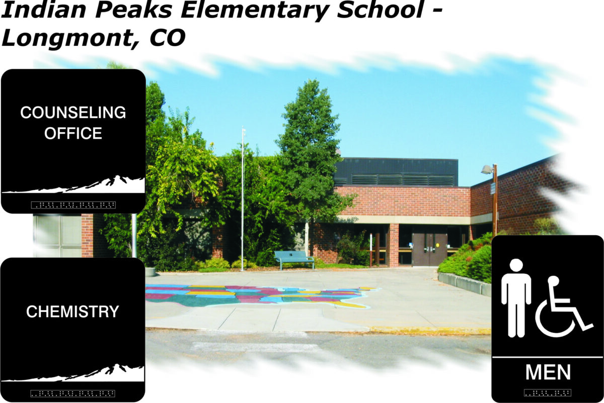 An exterior view of Indian Peaks Elementary School in Longmont, CO. The entrance area is lined with trees and bushes. Signs indicate locations: "Counseling Office" to the left, "Chemistry" to the lower left, and "Men" restroom with wheelchair access to the right.