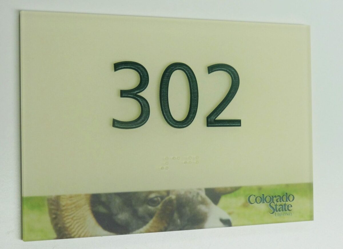 A room number sign displays the number "302" in raised green font. The lower part of the sign features a partial image of a ram and includes the "Colorado State" logo.