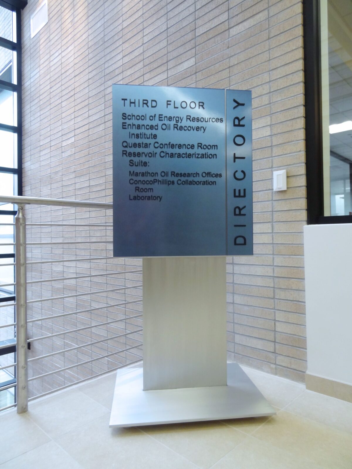 A metallic directory sign on a stand listing the locations of various rooms on the third floor, including the School of Energy Resources, Enhanced Oil Recovery Institute, Center for Energy Economics and Public Policy, Center for Fundamentals of Subsurface Flow, and others.
