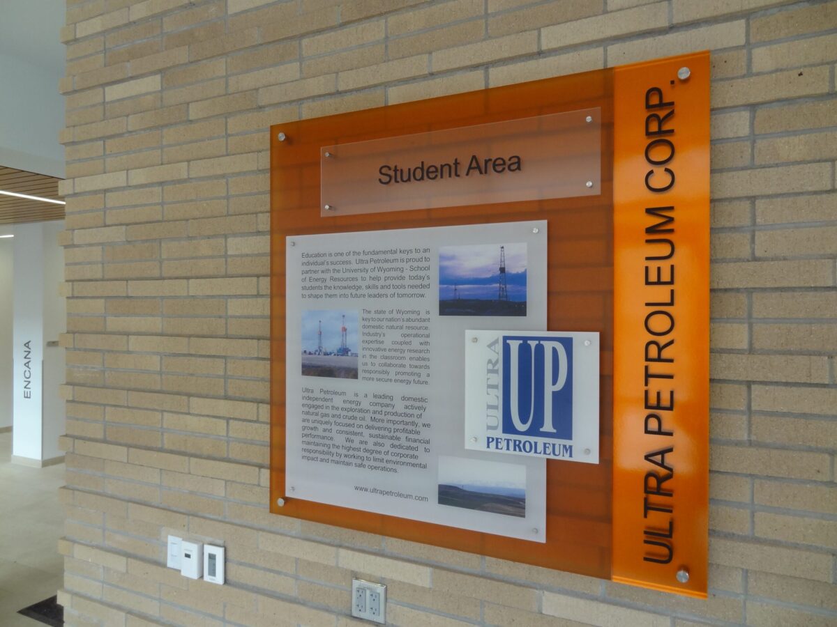 A wall-mounted informational display titled "Student Area" includes text and images, with the "Ultra Petroleum Corp" logo prominently featured alongside. The background is a light brown brick wall.