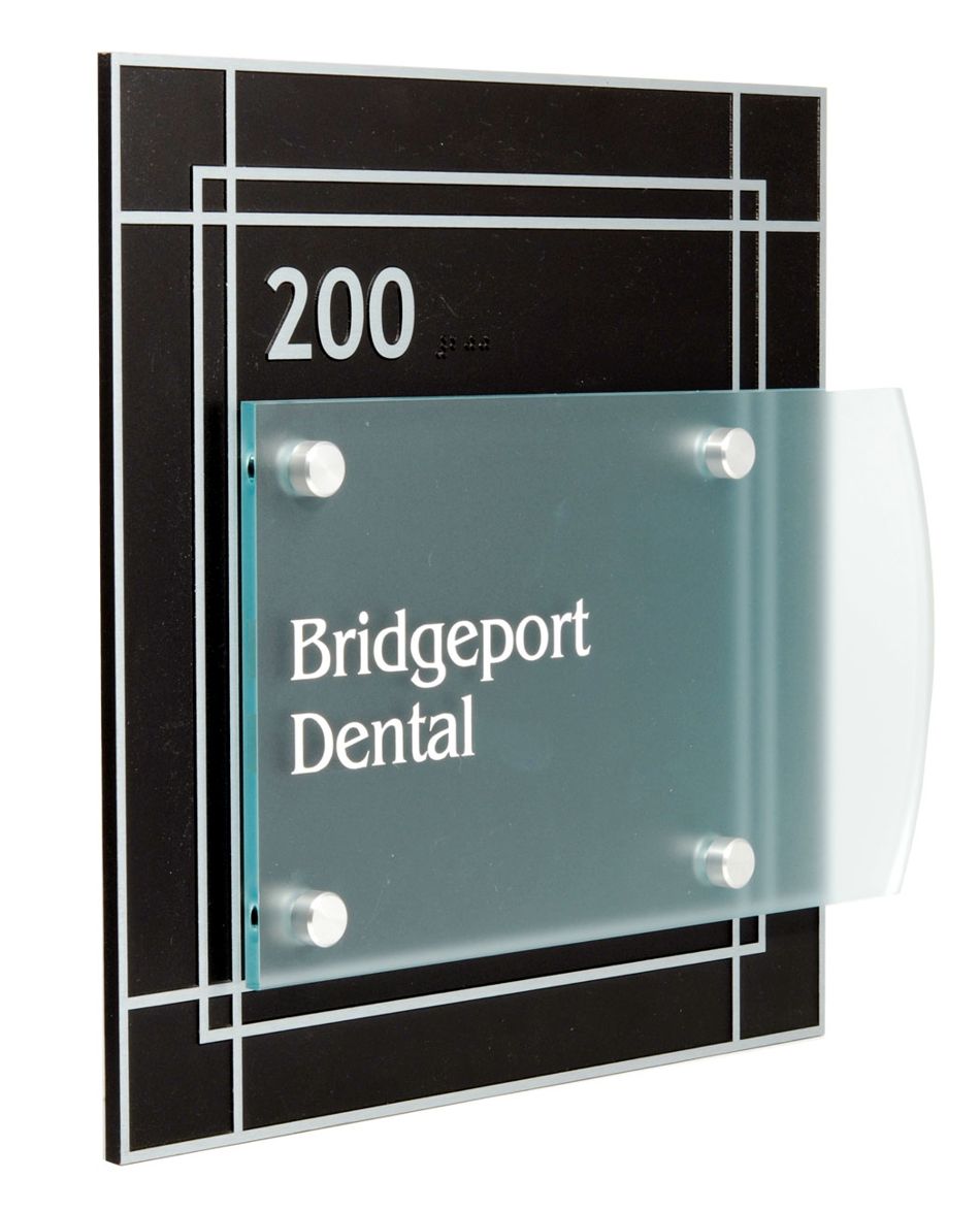 A black and silver sign displays the text "200" at the top and "Bridgeport Dental" in white letters on a frosted glass panel affixed to the sign. The design includes a series of thin horizontal and vertical lines for a modern look. Etched Zinc backplate, changeable green-glass acrylic nameplate.
