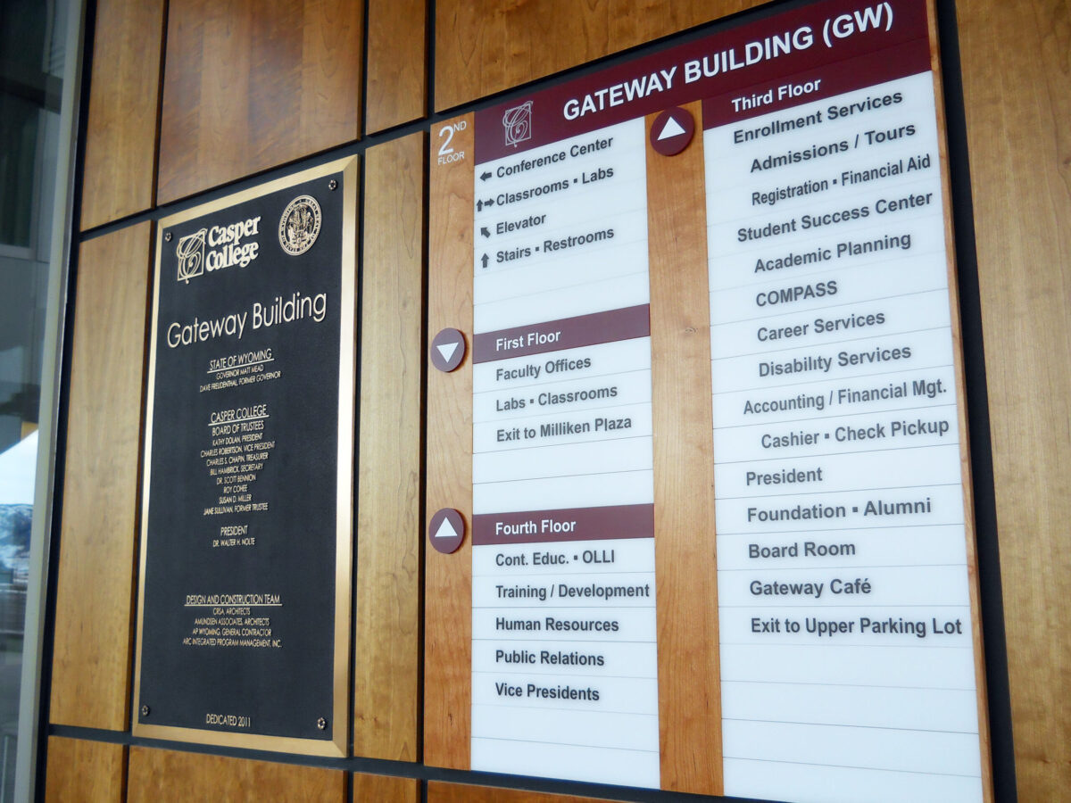 A directory sign inside the Gateway Building at City College, detailing floor listings for various departments and offices, including Admissions, Academic Services, Career Services, and the President's Office. Walls are wooden with black framed plaques.