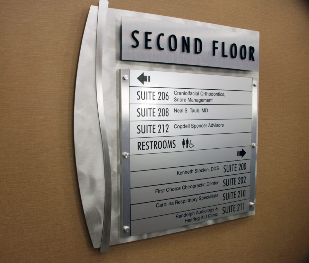 A directory sign indicates the locations of various suites and facilities on the second floor of a building. Listings include a craniofacial orthodontist, a podiatrist, and speaker advisors. It also notes the location of the restrooms, which are marked by male and female icons.