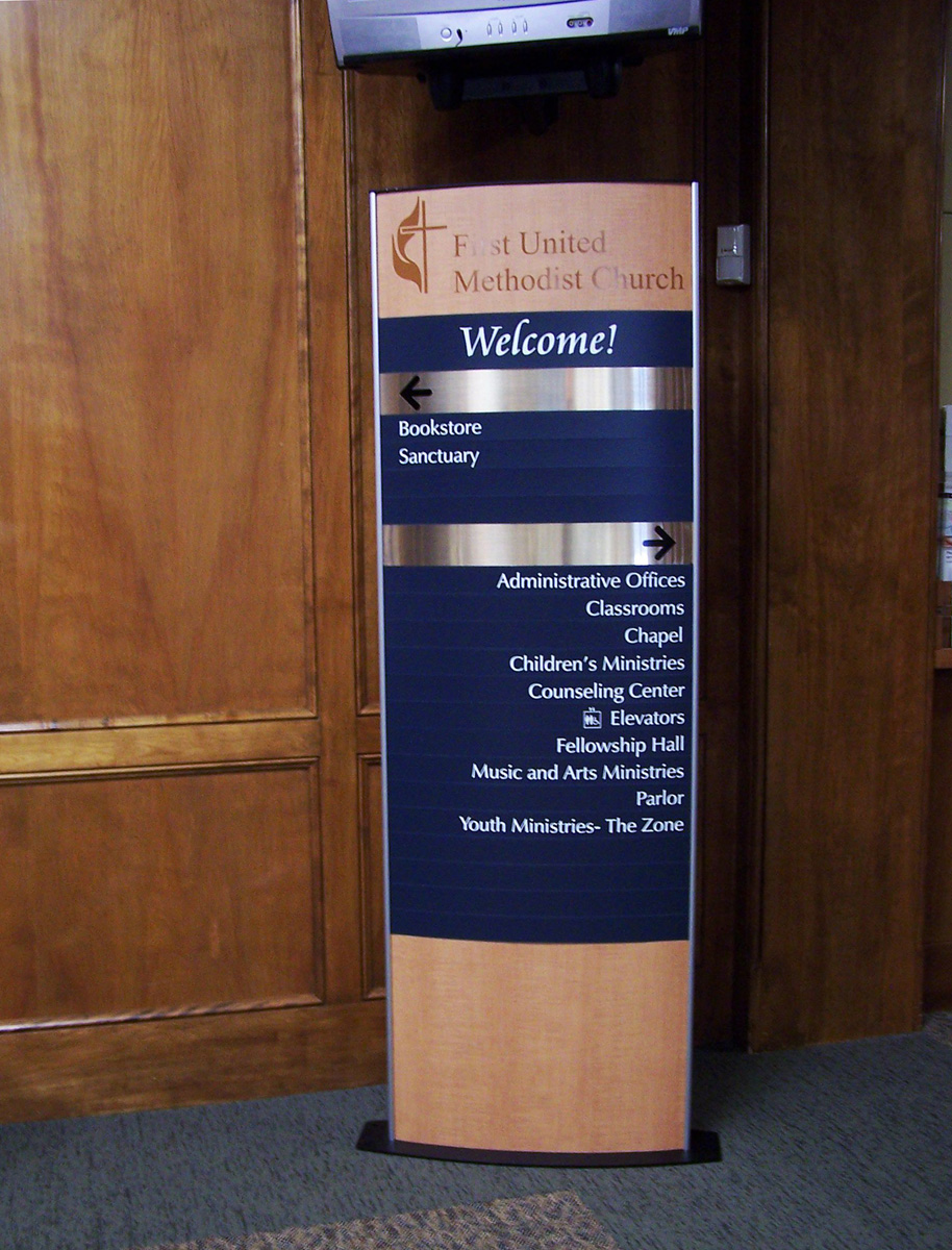 A stand-alone sign in a building with a header that reads "United Methodist Church - Welcome!" It lists various locations with arrows.