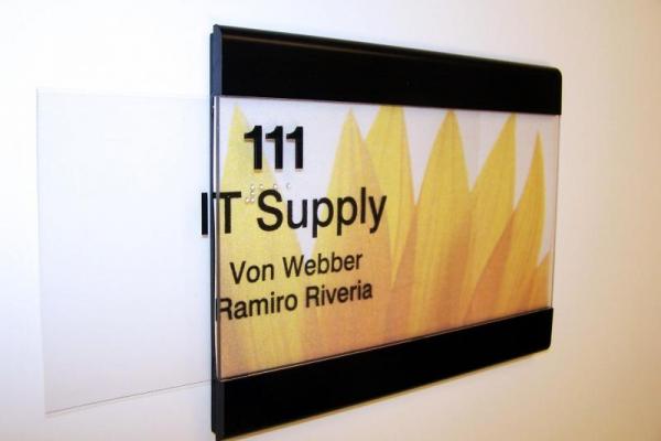 A modern office sign featuring the names Von Webber and Ramiro Riveria for IT Supply, room 111.