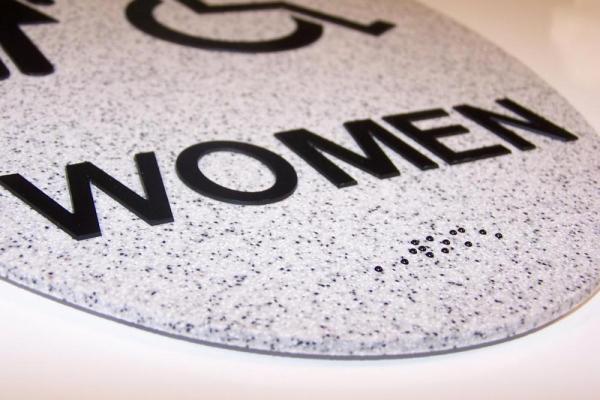 Speckled Women's restroom sign with braille