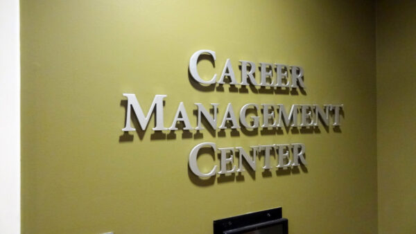 A wall sign with raised silver letters against a green background reads "Career Management Center".