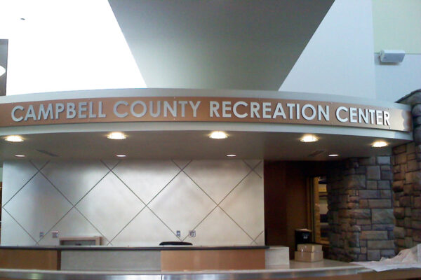 A reception desk at the Campbell County Recreation Center with a curved countertop and a sign above reading "Campbell County Recreation Center."