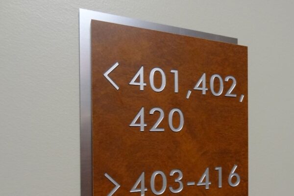 A wall-mounted sign with a brown background and silver edging displays room numbers: "< 401, 402, 420" for the left direction and "403-416" for the right direction.