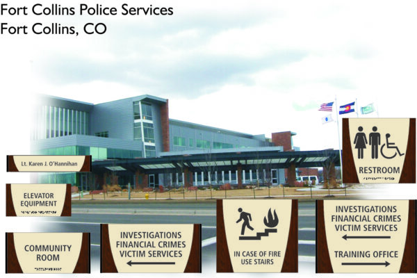 Photo of Fort Collins Police Services building in Fort Collins, CO. In the foreground, there are signs in English and Braille indicating locations for restrooms, elevator equipment, community rooms, and offices for investigations, financial crimes, and training.