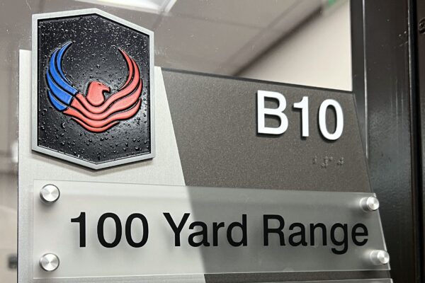 A sign with a black and red phoenix logo at the top, labeled "B10". Below it reads "100 Yard Range". The bottom part of the sign states "Range Sponsored by Burris" with the Burris company logo.