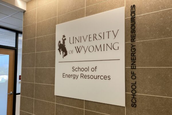A sign on a tiled wall reads "University of Wyoming School of Energy Resources" with the school's logo. To the right of the sign, "School of Energy Resources" is written vertically. The area features a door and part of a window.