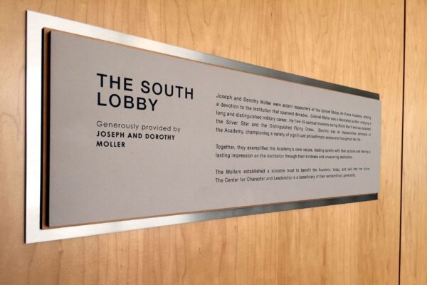 A metal plaque mounted on a wooden surface reads: "The South Lobby. Generously provided by Joseph and Dorothy Moller." It includes a paragraph of text describing the lobby's features and its purpose.