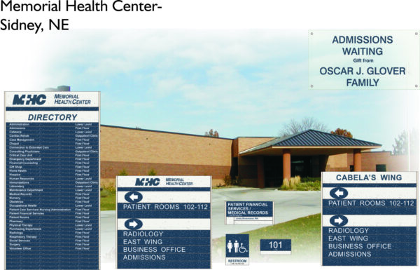Exterior of Memorial Health Center in Sidney, NE, with signs showing directions to admissions, waiting area, patient rooms, radiology, business office, financial services, and Cabela's wing. Blue sky with some clouds and greenery visible.