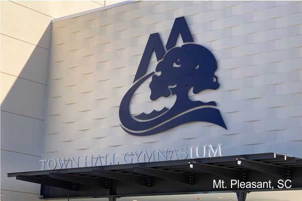 The image shows the exterior facade of a Town Hall or Gymnasium building in Mt. Pleasant, South Carolina. The building features a large logo above the entrance, consisting of stylized mountain peaks and a tree. The text "Mt. Pleasant, SC" is visible in the bottom right corner.