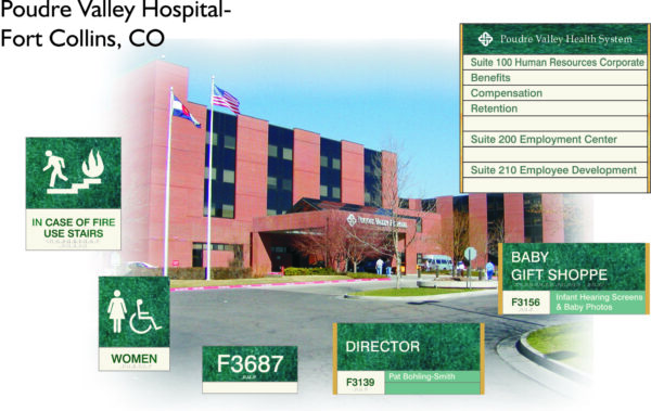 Exterior view of Poudre Valley Hospital in Fort Collins, CO, showing various directional signs, including Human Resources, Employee Center, Employee Development, fire safety, restrooms, baby gift shop, and a Director's office. American and state flags are visible.
