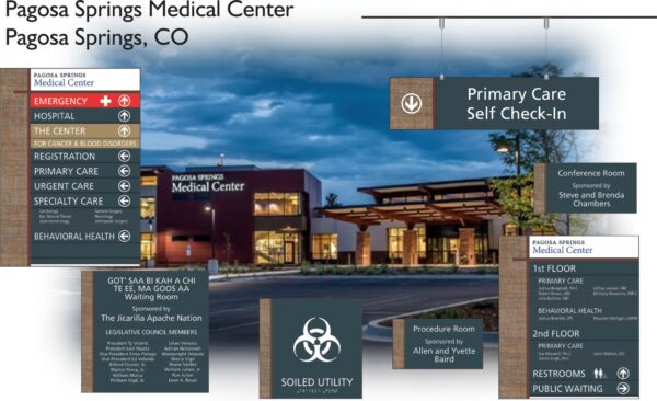 An image of the Pagosa Springs Medical Center in Pagosa Springs, CO. It shows the building's exterior at dusk, with various signboards indicating the locations of emergency, primary care, self check-in, conference rooms, procedures, and other medical services.