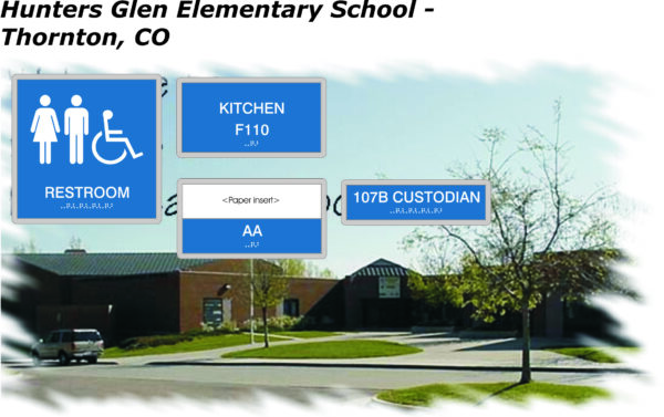 An exterior view of Hunters Glen Elementary School in Thornton, CO. Four signs are overlaid: "Restroom" with an accessibility symbol, "Kitchen F110", "107B Custodian", and "AA" with "Paper Insert". All signs include Braille. The school is surrounded by grass and trees.