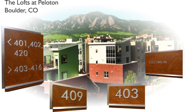 Image of The Lofts at Peloton, located in Boulder, CO, with a backdrop of mountains. There are three apartment numbers, 401-402-420, 403-416, and individual signs for 409 and 403. An additional sign reads "Electrical". The buildings are modern with various color facades.