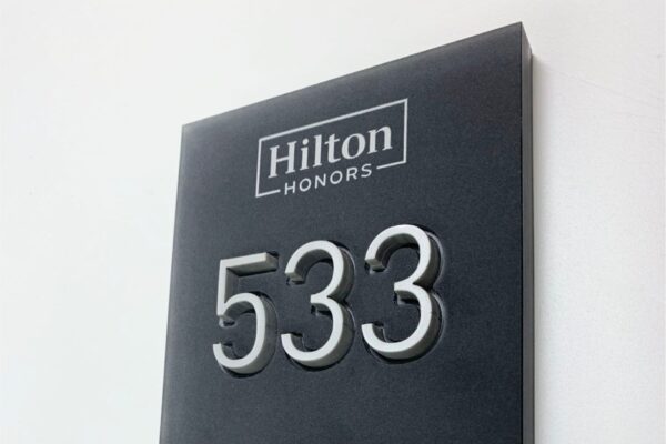 A hotel room sign for room 533, displaying the Hilton Honors logo at the top, a wheelchair accessibility symbol below the room number, and braille text at the bottom. The DoubleTree by Hilton logo is in the bottom left corner.