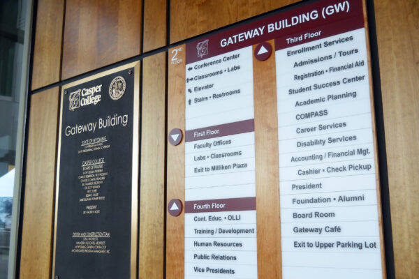 A directory sign inside the Gateway Building at City College, detailing floor listings for various departments and offices, including Admissions, Academic Services, Career Services, and the President's Office. Walls are wooden with black framed plaques.