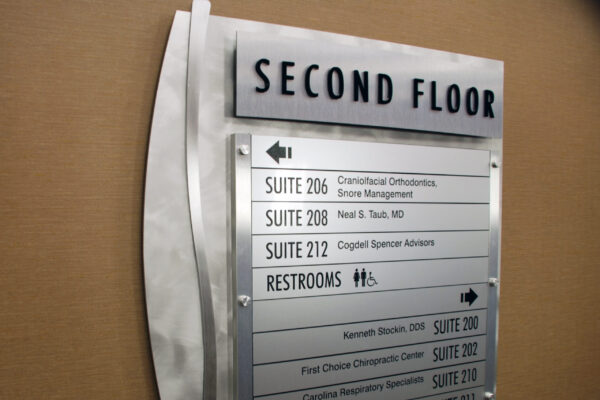 A directory sign indicates the locations of various suites and facilities on the second floor of a building. Listings include a craniofacial orthodontist, a podiatrist, and speaker advisors. It also notes the location of the restrooms, which are marked by male and female icons.