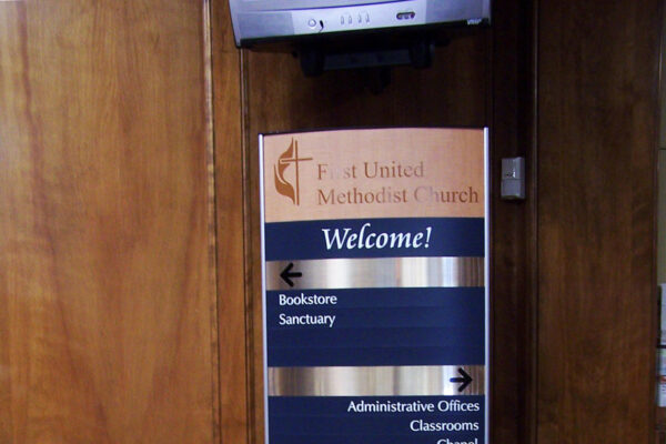 A stand-alone sign in a building with a header that reads "United Methodist Church - Welcome!" It lists various locations with arrows.