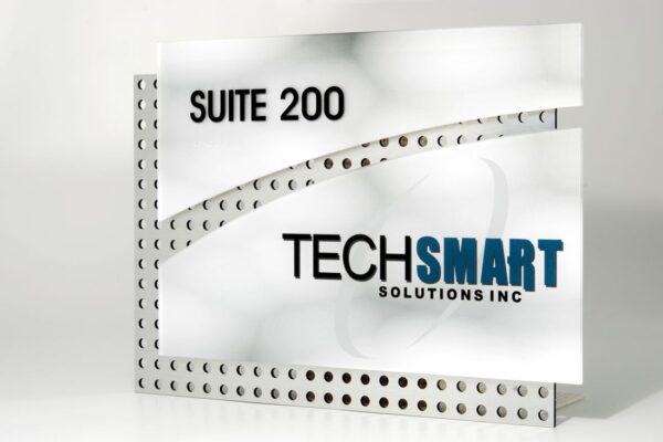 A sign for TechSmart Solutions Inc. The sign features the text "SUITE 200" at the top and "TECHSMART SOLUTIONS INC" at the center. The background has a sleek design with perforated metal elements and smooth white panels.