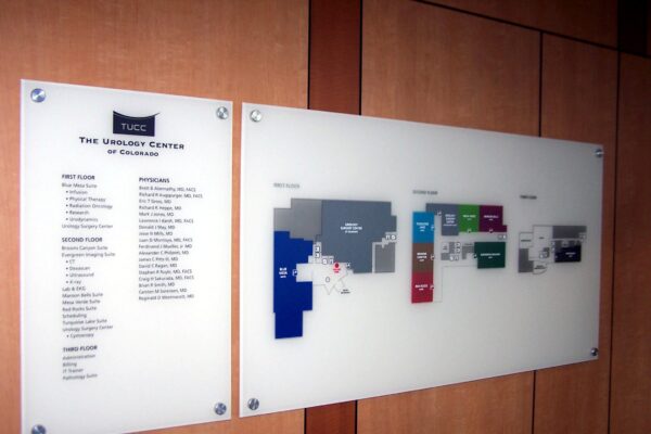 A wall-mounted directory and map at The Spencer Center of Delaware. The left panel lists services and locations, while the right panel shows a color-coded floor plan with labeled rooms. The background wall is wooden.